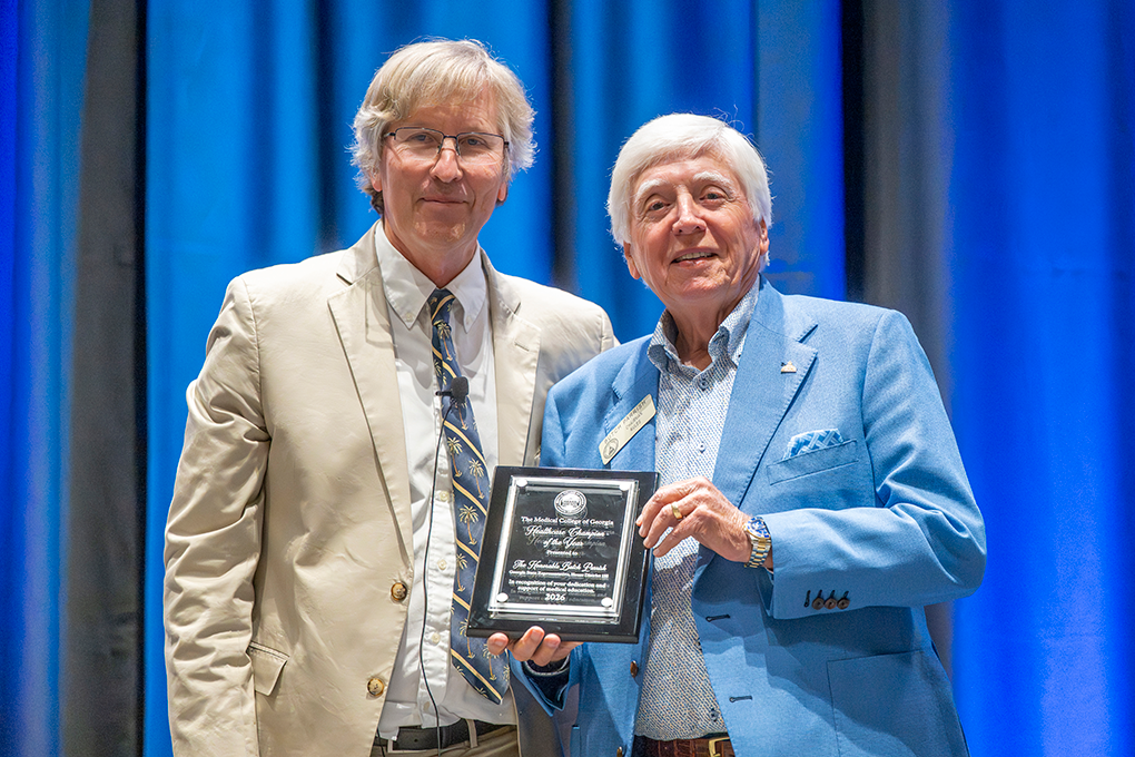 Two men in business dress, one holding a plaque.