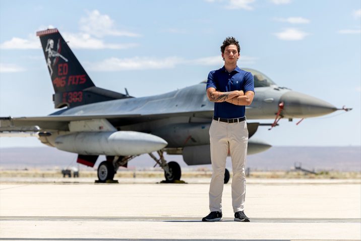 A man standing with his arms crossed in front of an airplane.