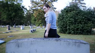 Woman standing next to gravestone