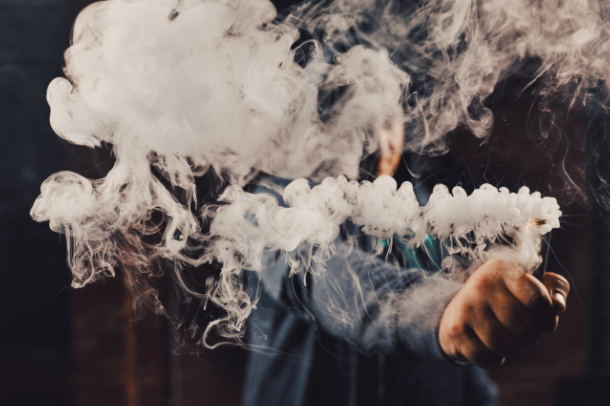 image of man vaping with vape smoke taking up most of the shot.