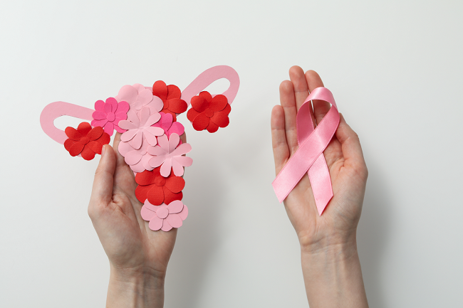 Cervical Cancer Secreening image with a uterus shape covered in flowers and a pink cervical cancer ribbon held by a woman's hands