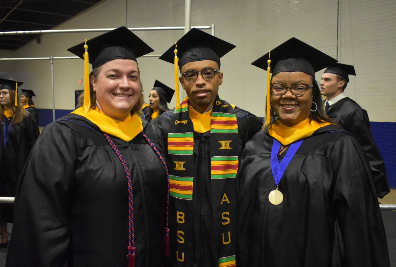 two girls and a guy in cap and gown 