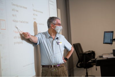 Professor pointing at whiteboard 