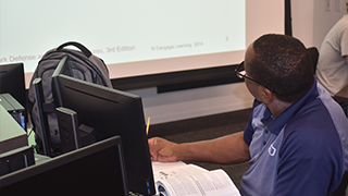 Student at a computer looking at the front of the classroom