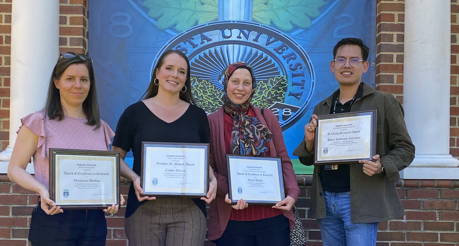 Grad Day photo with 3 woman and one man posing for camera with rewards