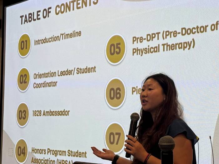 female student holding a microphone in front of a screen