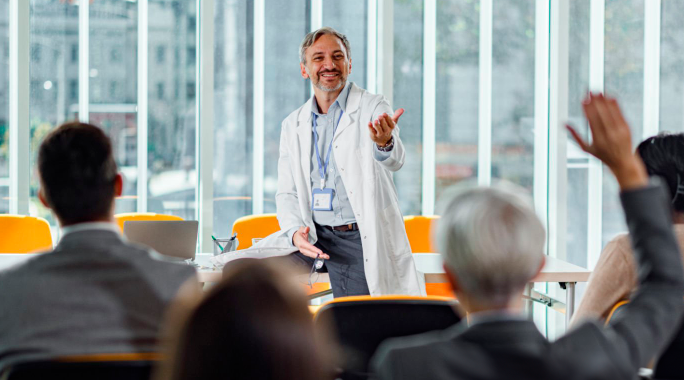 Doctor pointing to man with hand raised in audience