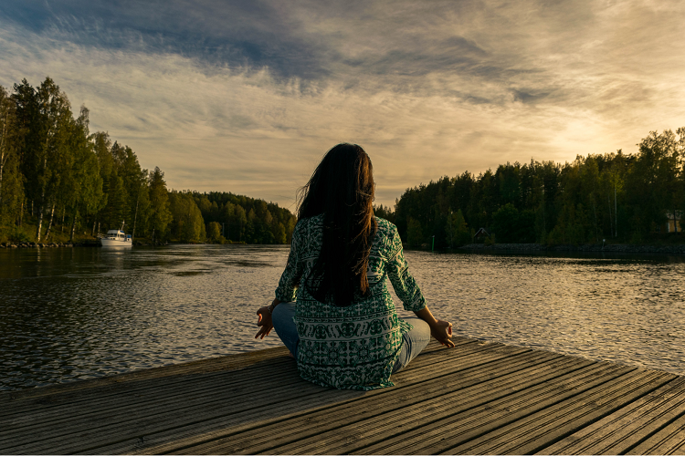 woman meditates on a dock