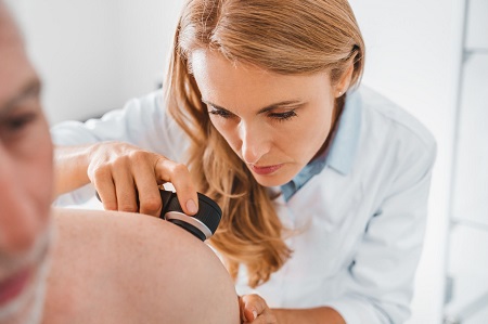 dermatologist looking closely at patient's skin