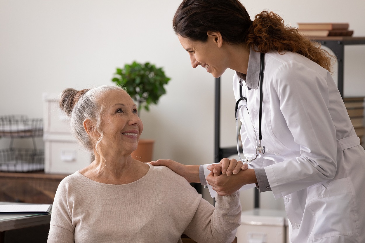 Female patient smiles up at doctor smiling at her.