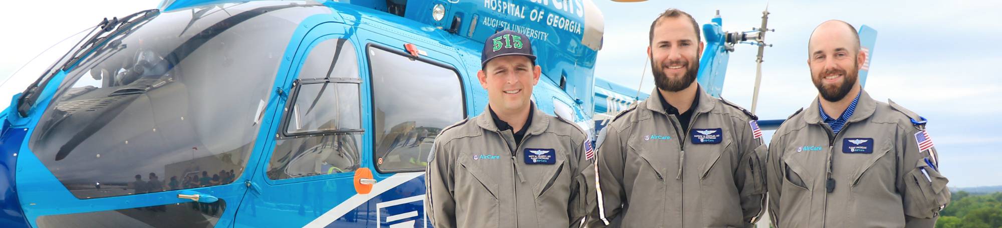 Three doctors pose in front of helicopter