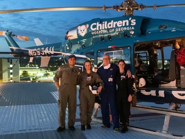 two men and two women stand in front of a CHOG helicopter