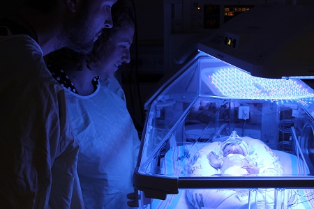 parents looking at baby in incubator