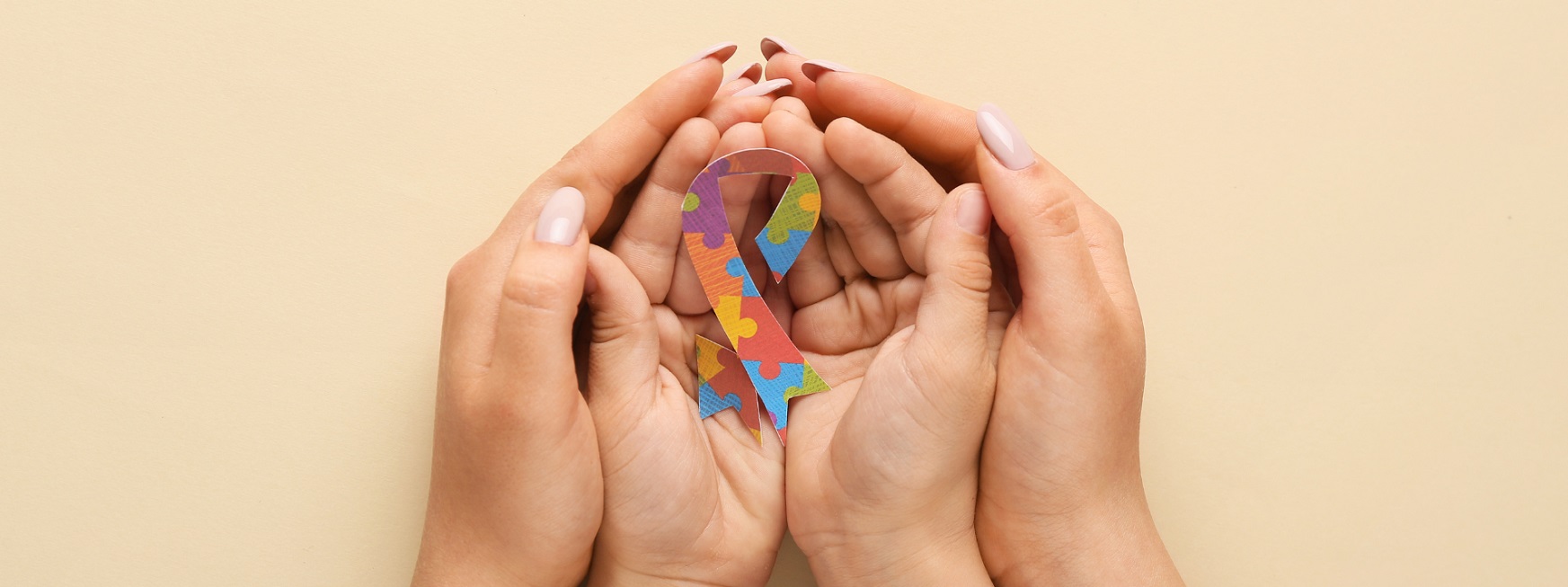 mother holding childs hands with autism awareness ribbon