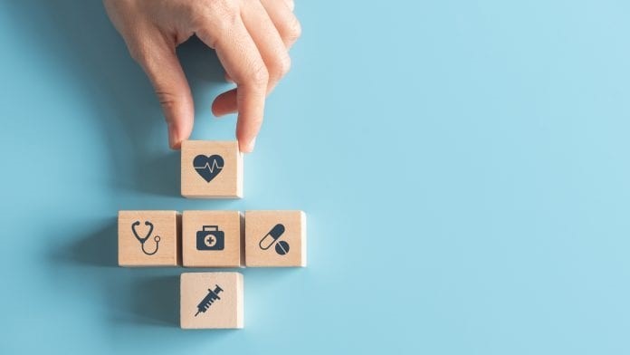 Man putting down tiles with medical icons on them.