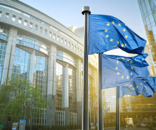 Flags with European Union emblem flying outside of a building