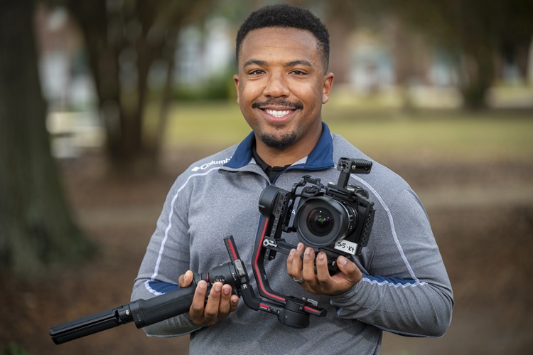 man smiling holding camera