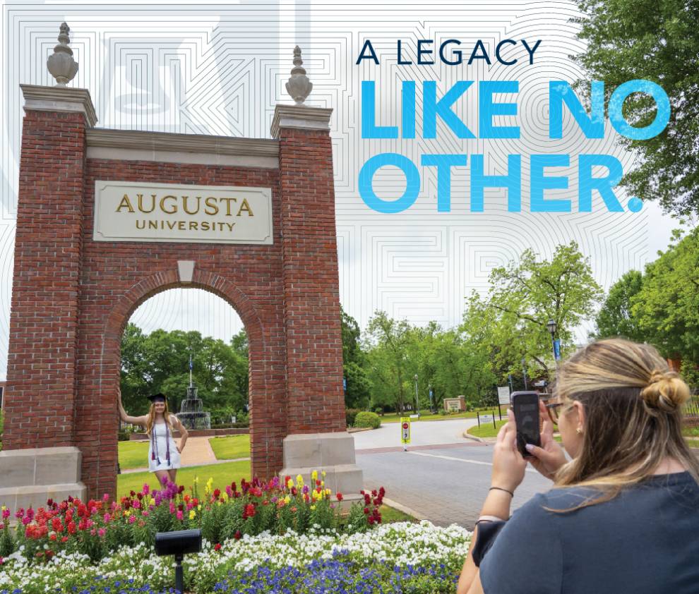 someone taking a photo of the augusta university arch with words that says a legacy like no other