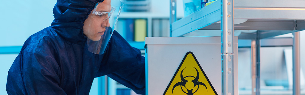 Worker wearing a protective radiation suit while handling radioactive materials in a lab.