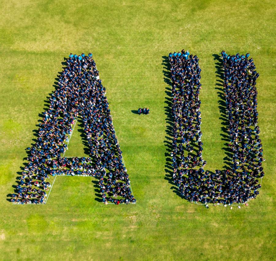 Class of 2030 class pic group of people gathered together inside white outlined A-U letters