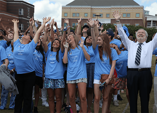 Dr. Keel with students raising their hands to the sky