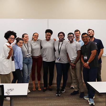 Student Reciving There White Coat A Future Faculty participant group stands together, smiling, in front of a whiteboard.