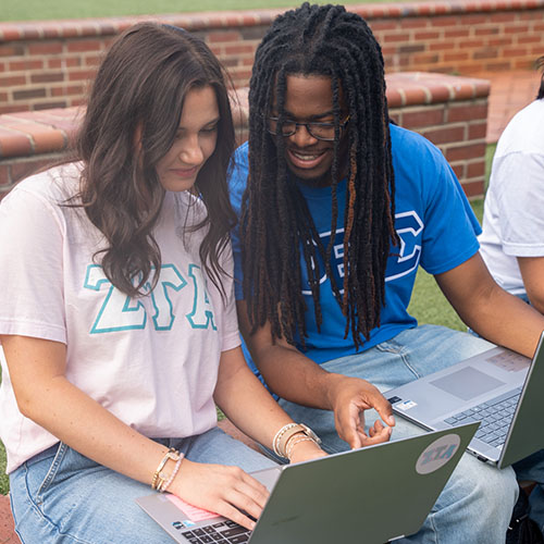Two students working over laptop