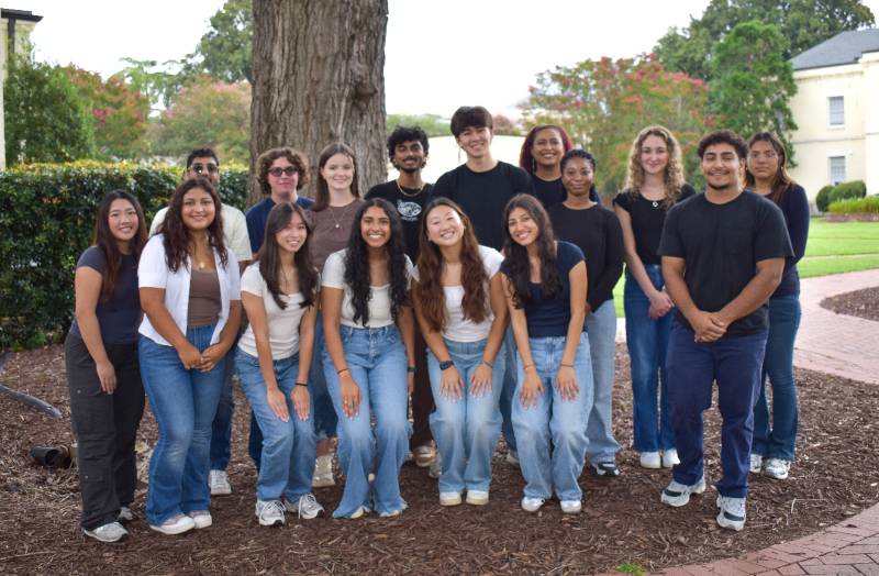 group of male and female students standing in front of a tree
