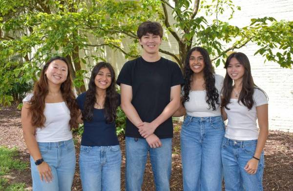 four women and one man standing together in front of a tree