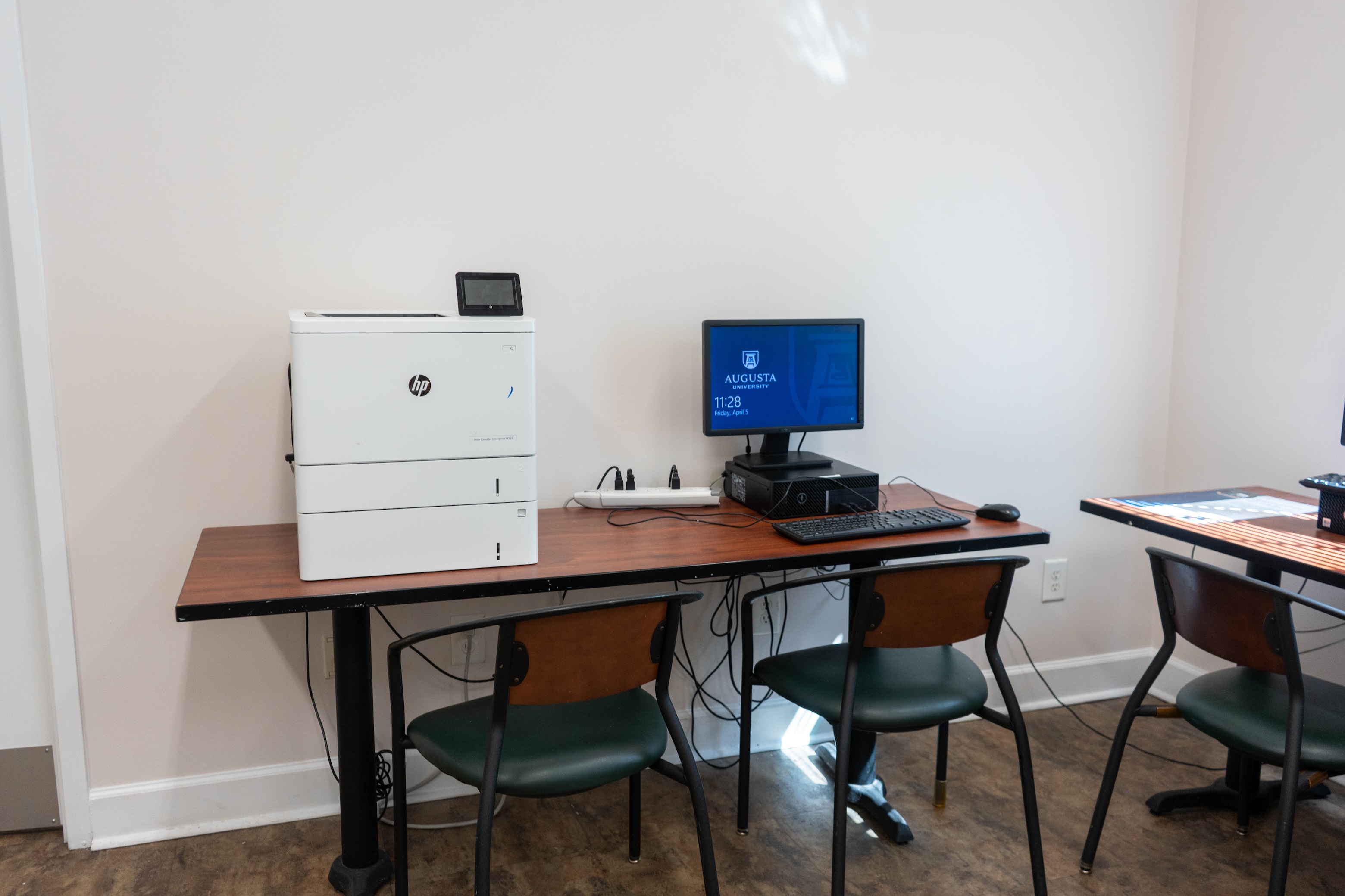 University Village computer lab with desk and chair. Personal Computer with printer next to it.