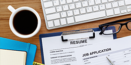 Job application and resume in front of a computer keyboard