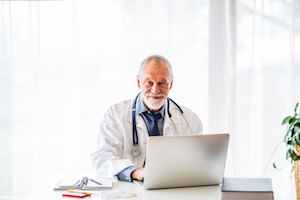 Man with stethoscope at laptop