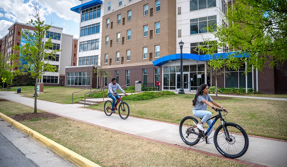 Two students carry moving supplies outside of the residence halls