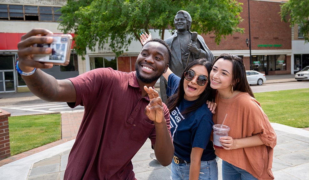 Group of masked students greets others at the fountain