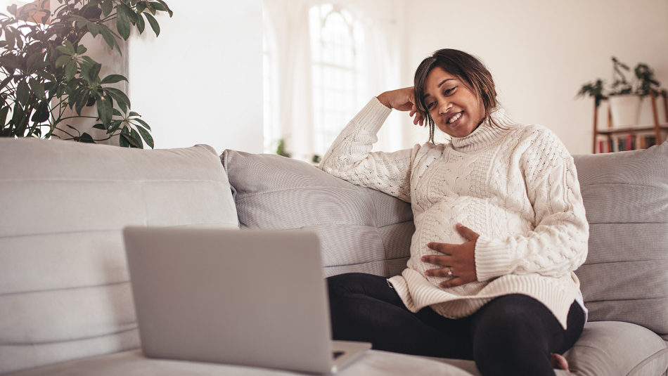 Latin Pregnant woman looks at computer