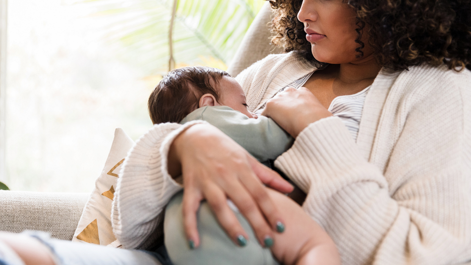 Mother breastfeeding her newborn near a windwo