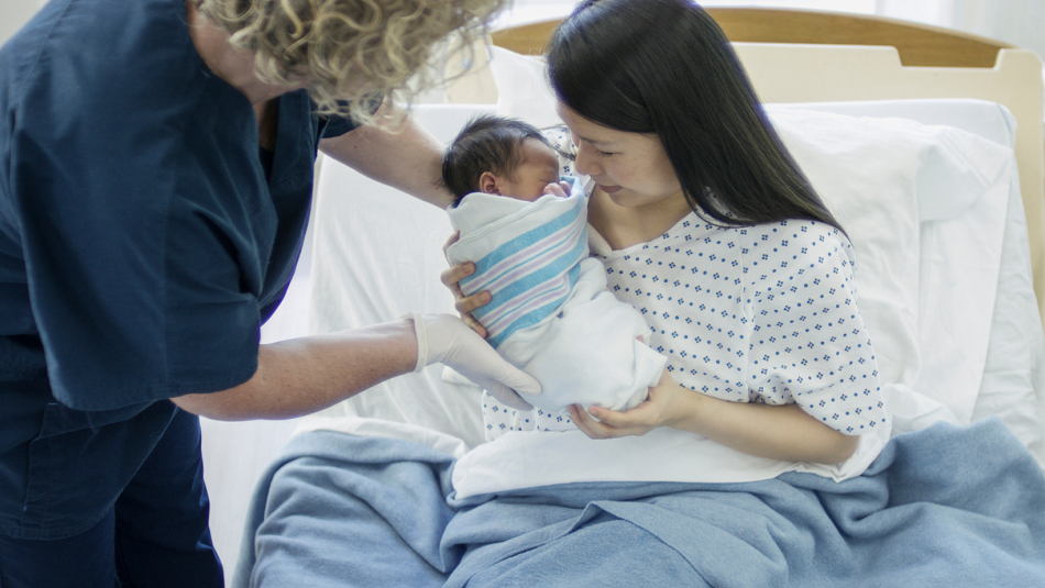 Nurse hands a baby to mom