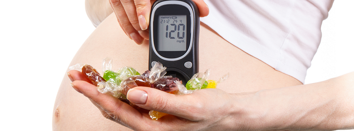 Pregnant woman holding candy and a blood sugar tester