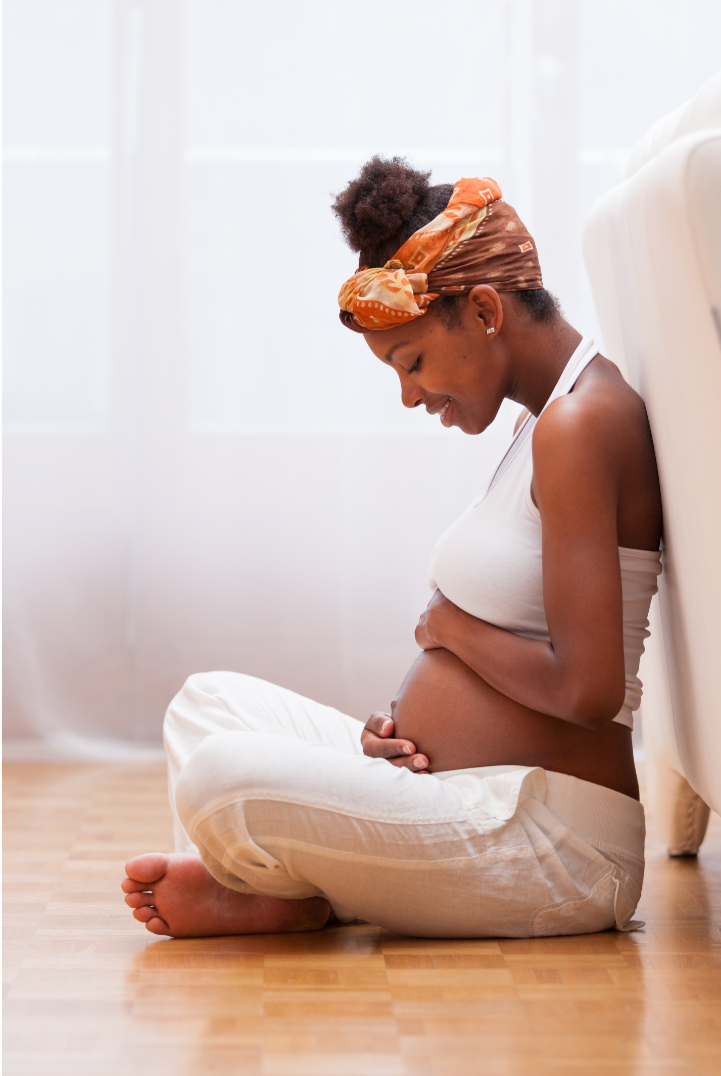 Pregnant woman smiling looking at her pregnant bely