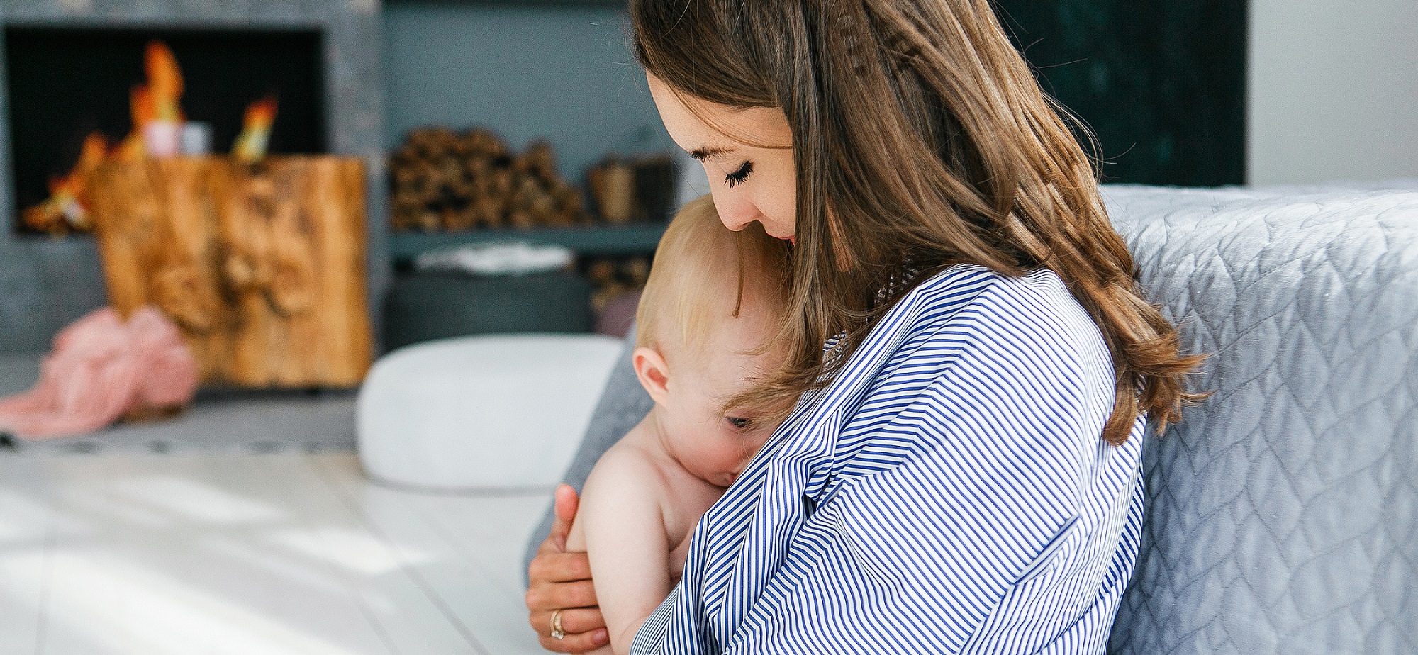 Young mother breastfeeding a baby in her home