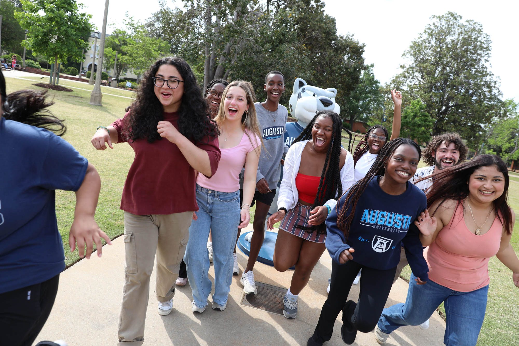 Augusta University students laugh together near the Augustus statue.