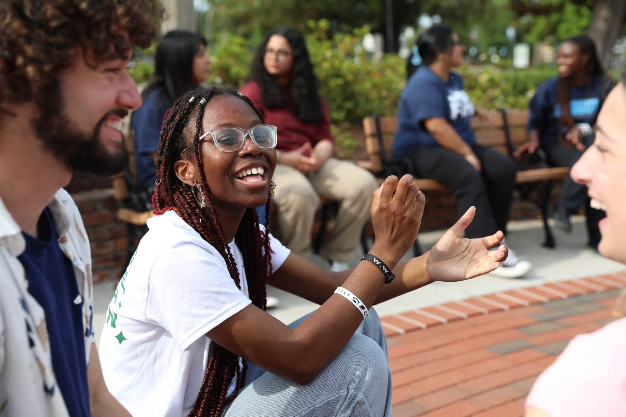 A student facilitator leads a conversation with a group outdoors on campus.