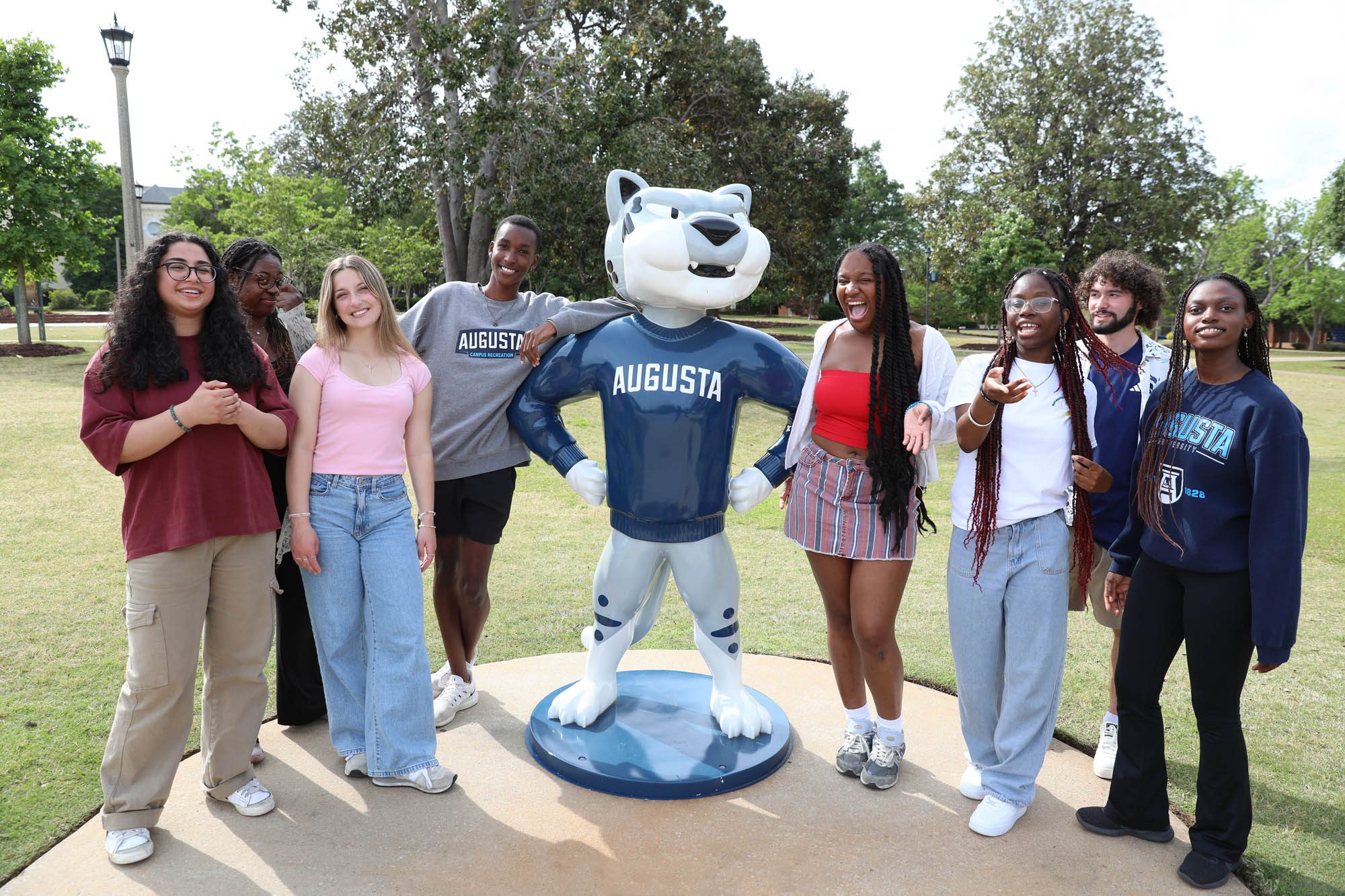 A group of Augusta University students gathers around the Augustus statue on campus.