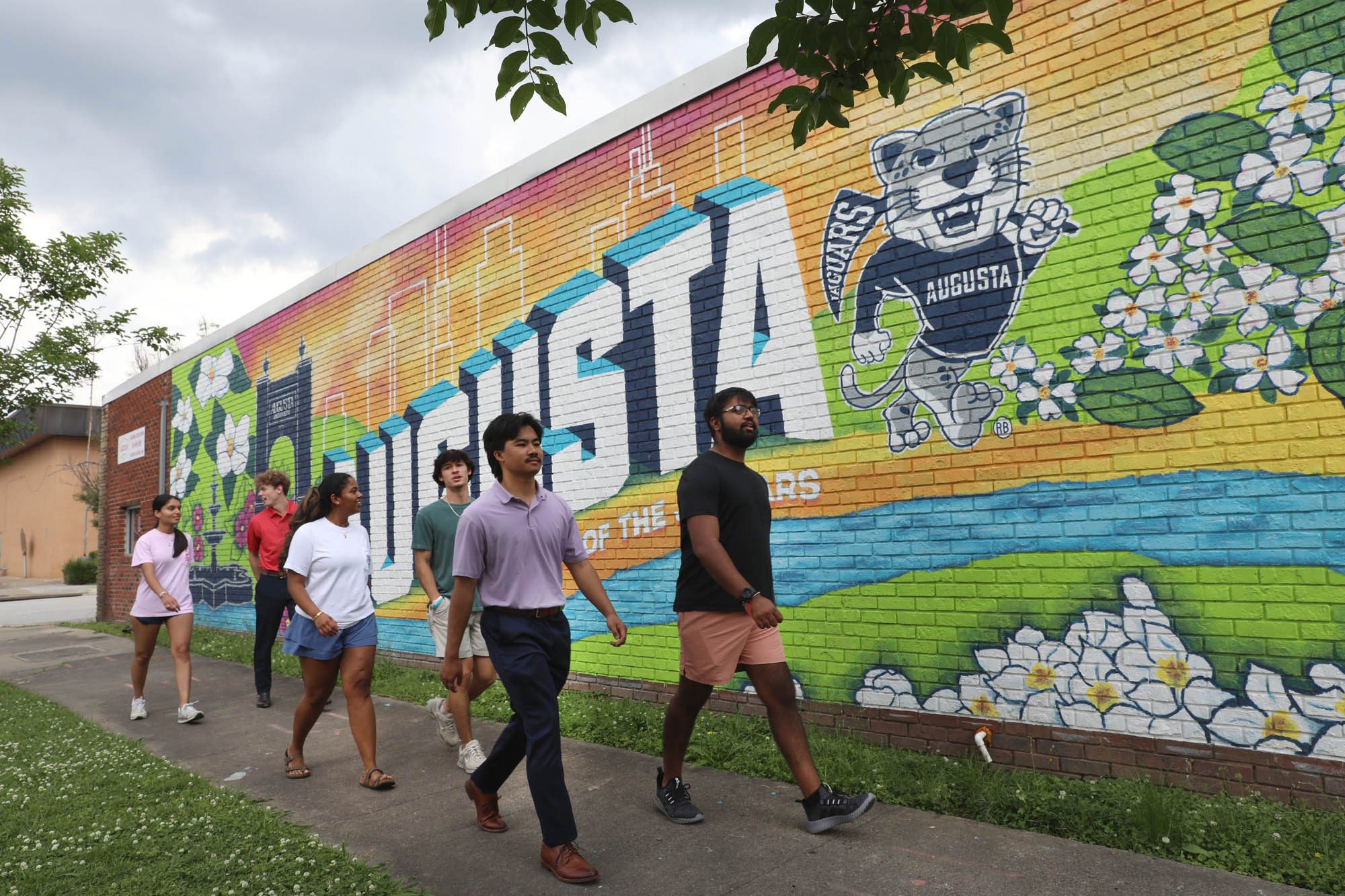 Augusta University students walk beside a colorful university mural in downtown Augusta.