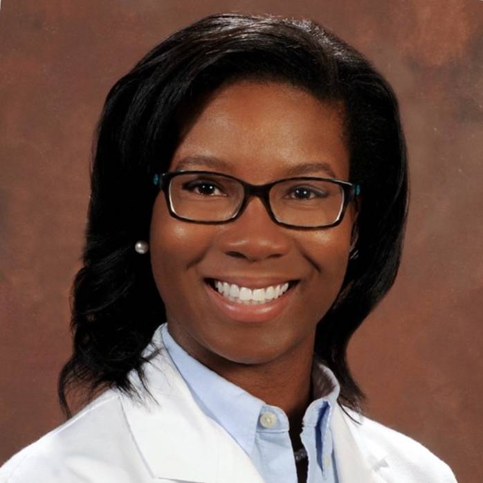 Headshot on brown background in white coat of Dr. Ashley Nunnally