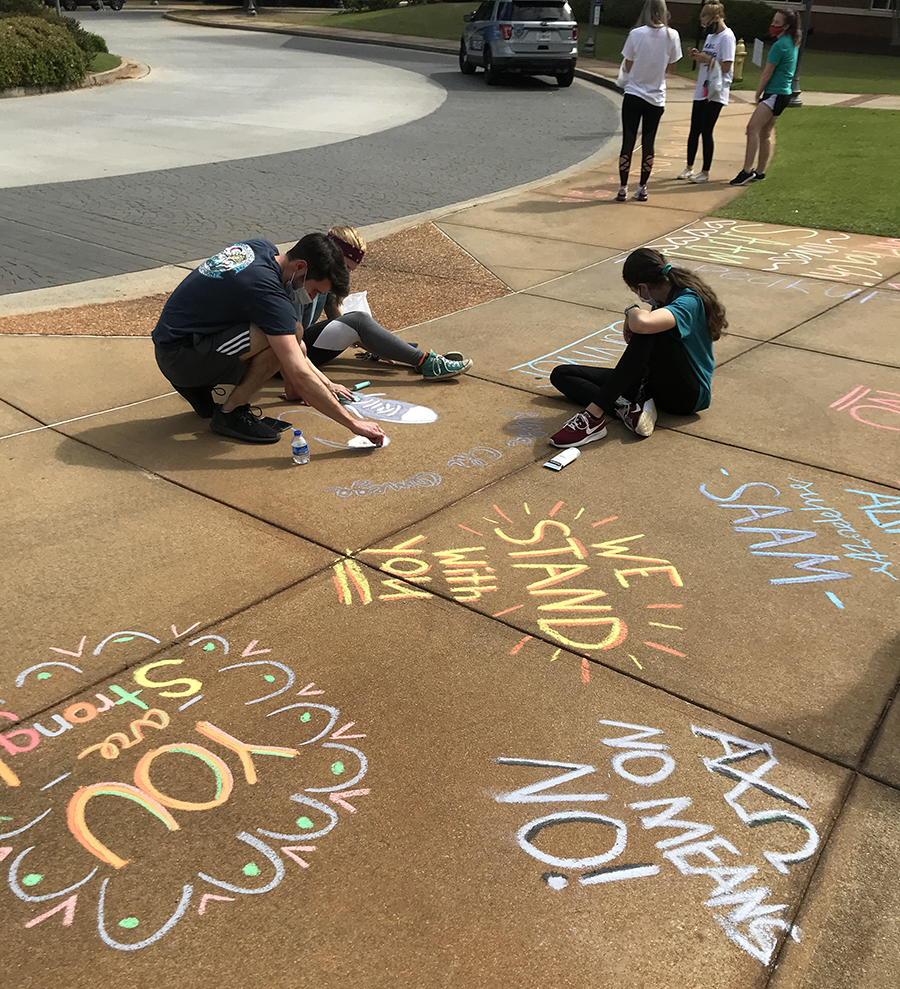 Student writing on sidewalk with chalk