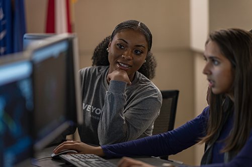 Two students looking at computer screen in a classroom