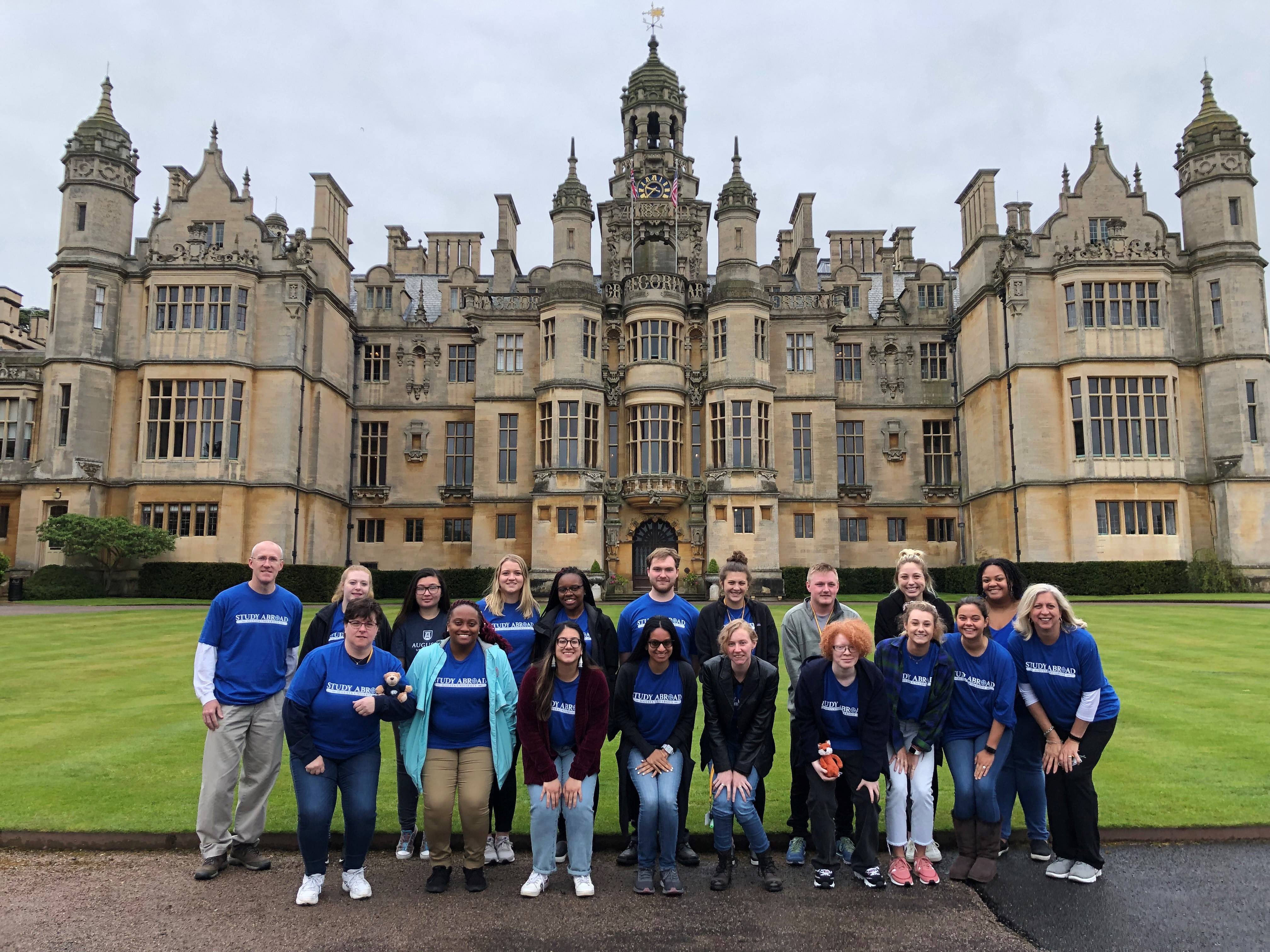 a group poses in front of a castle
