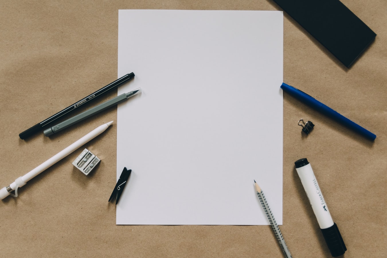 blank paper surrounded by writing utensils